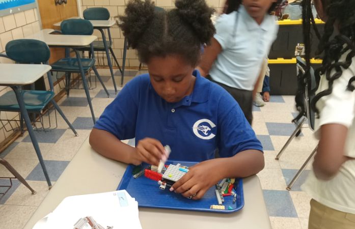  Student working on building her robot with legos.
